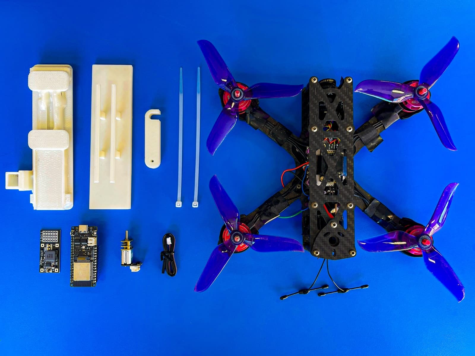 Drone frame and components laid out on a bright blue surface